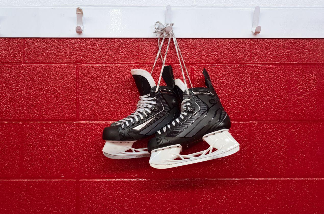Eishockeyschlittschuhe mit Kufenschonern an Haken aufgehängt – korrekte Aufbewahrung
