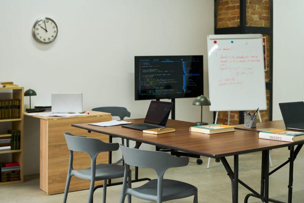Online Seminarverwaltung im Bildungswandel – moderner Seminarraum mit Whiteboard, Laptops und Bildschirm als Symbol fuer hybride Lernformate