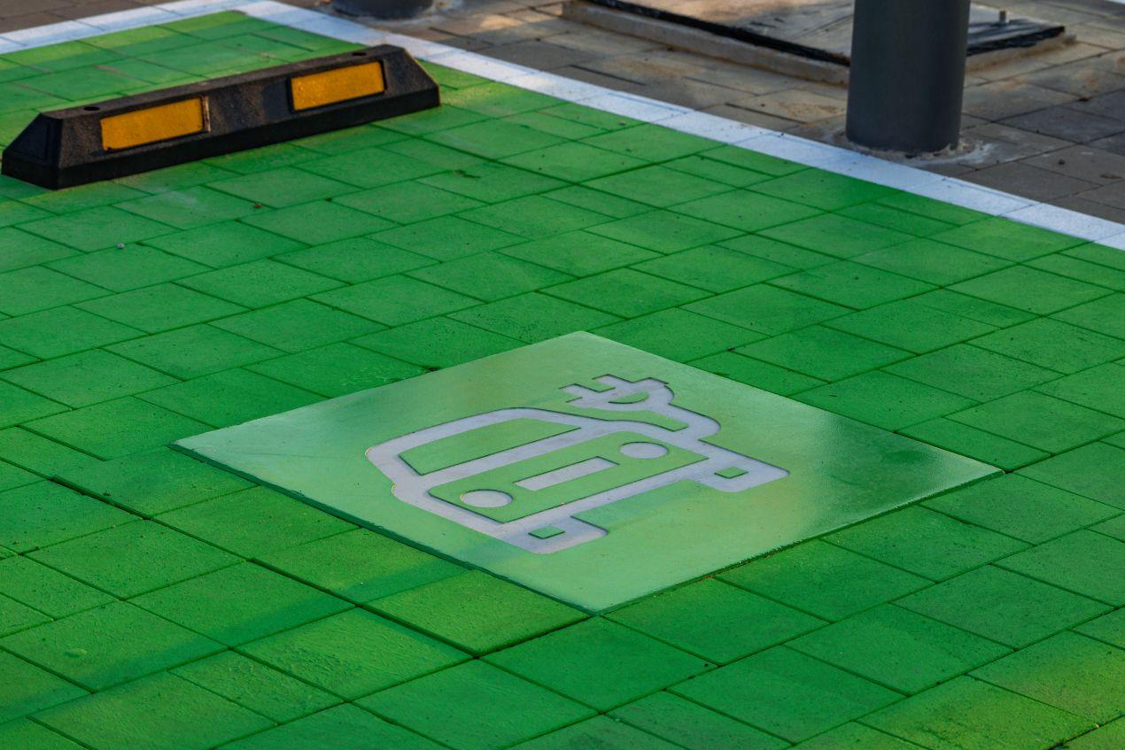Gruene Bodenflaeche mit E-Auto Symbol markiert Parkplatzmarkierung E-Auto fuer Ladezone