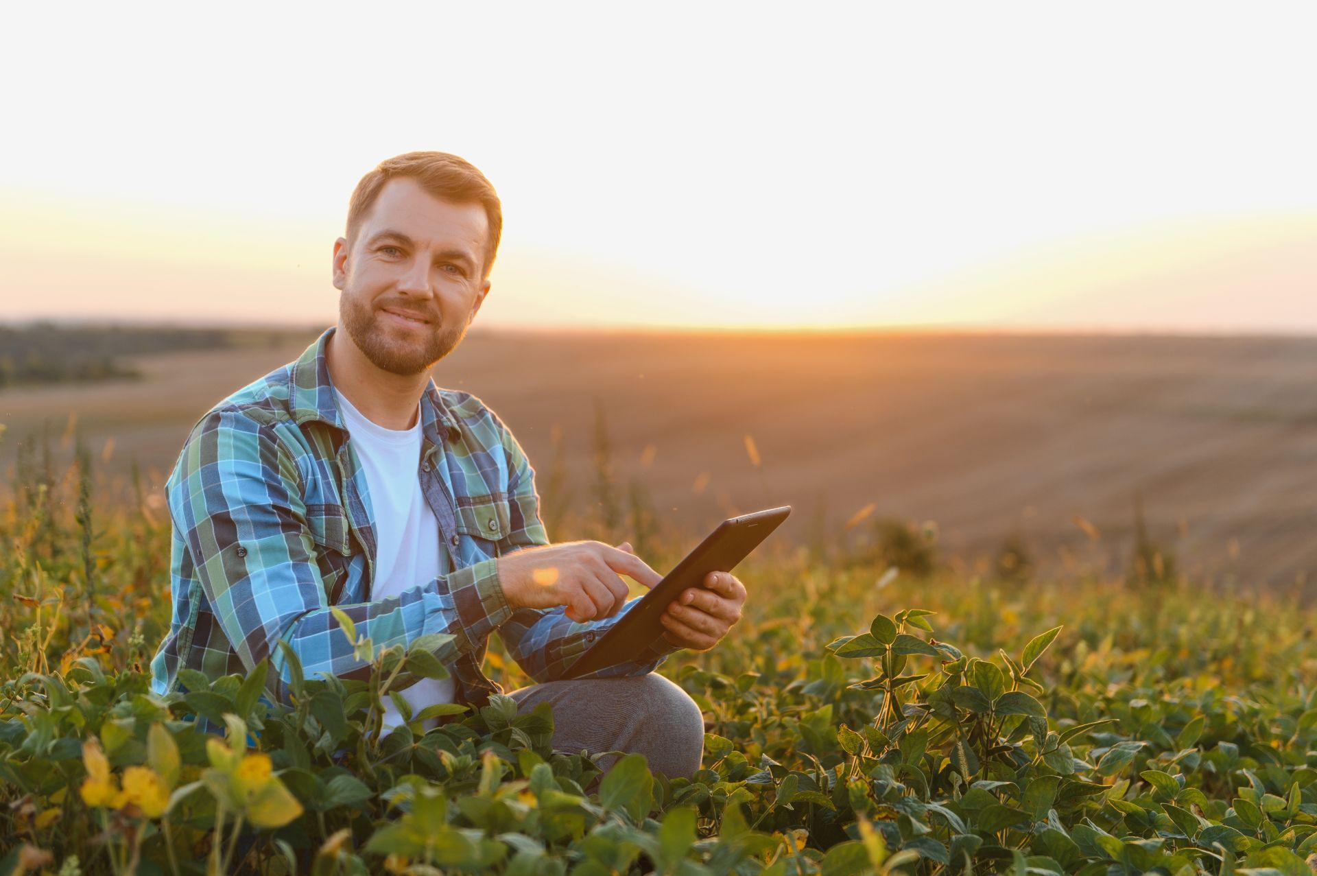 Junger Landwirt mit Tablet auf Feld bei Sonnenuntergang, steht fuer Digitalisierung, Smart Farming und vernetzte Fluessigduengertank Systeme