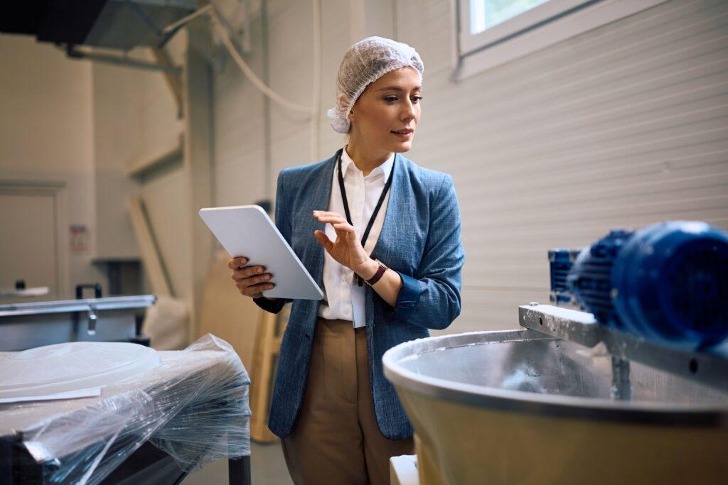 Qualitätsmanagerin überprüft Produktionsanlage im Reinraum – Reinraumreinigung sichert Präzision und Prozesssicherheit in der Industrie