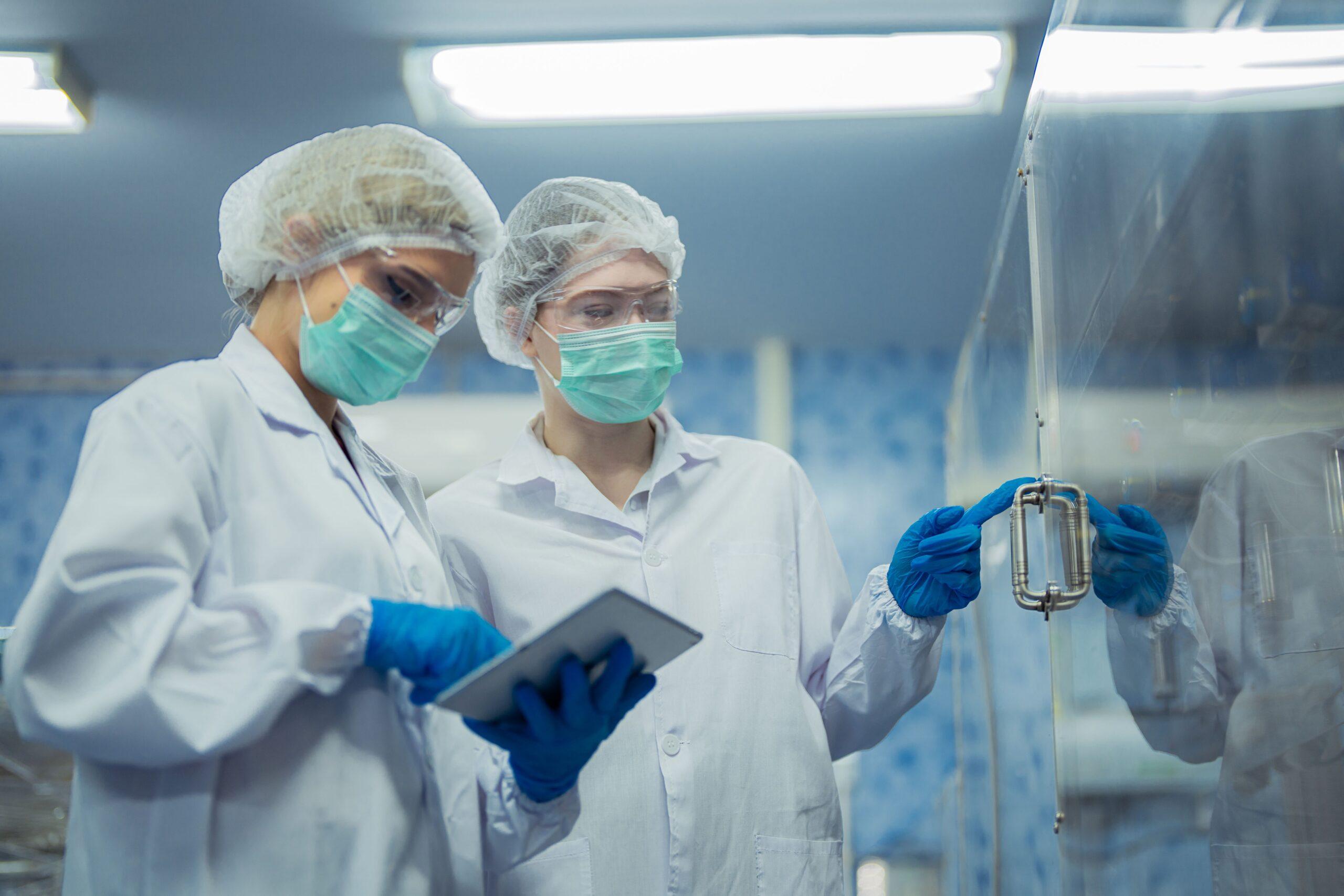 Zwei Fachkräfte im Reinraum überprüfen Produktionsabläufe