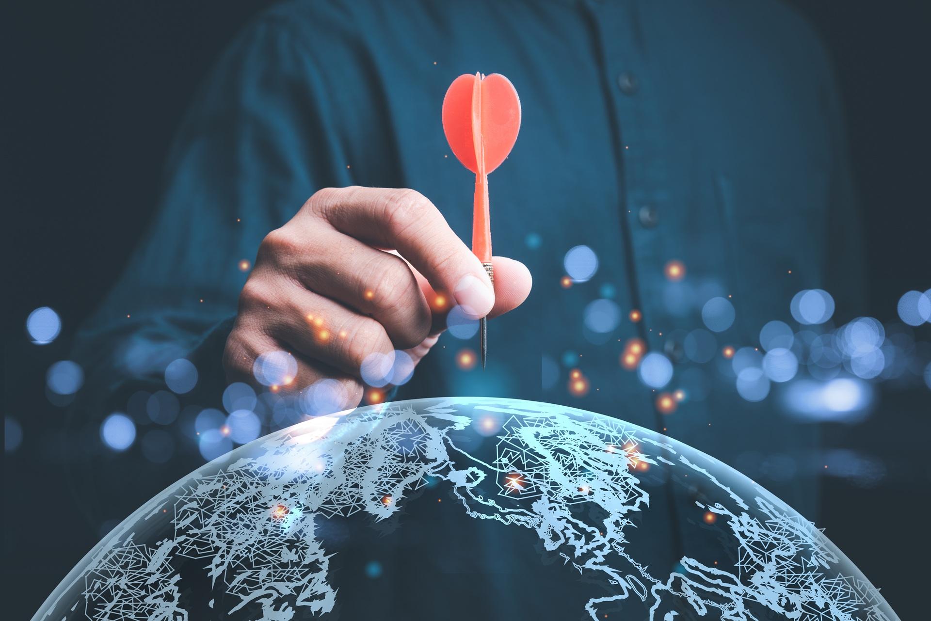 Hand setzt Dartpfeil auf eine Weltkugel | Übersetzungsbüro